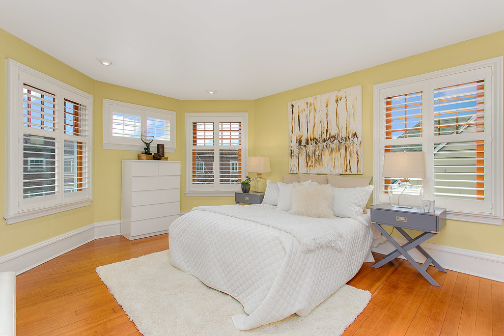 Modelo de habitación de invitados minimalista grande con paredes amarillas y suelo de madera clara