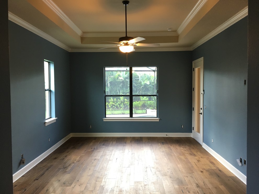 Exemple d'une grande chambre parentale tendance avec un mur bleu, parquet foncé et un sol marron.