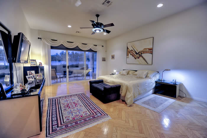 フェニックスにある巨大なコンテンポラリースタイルのおしゃれな主寝室 (ベージュの壁、磁器タイルの床、標準型暖炉、石材の暖炉まわり)