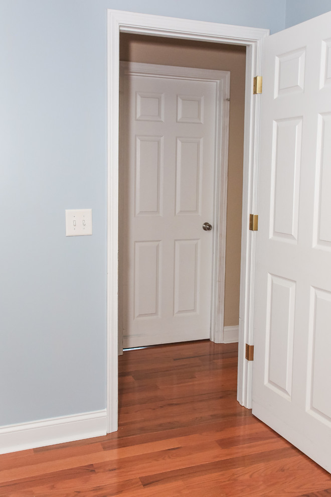 Ejemplo de dormitorio principal actual de tamaño medio con paredes azules, suelo de madera en tonos medios y suelo marrón