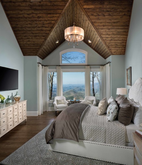 A luxurious bedroom with a spacious bed and an elegant chandelier hanging from the ceiling and icy blue colors.
