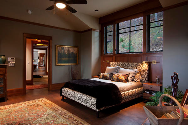 Cette image montre une grande chambre parentale craftsman avec un mur gris, un sol en bois brun et un sol marron.