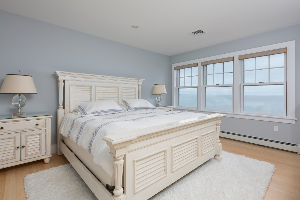 Diseño de habitación de invitados marinera sin chimenea con paredes azules y suelo de madera clara