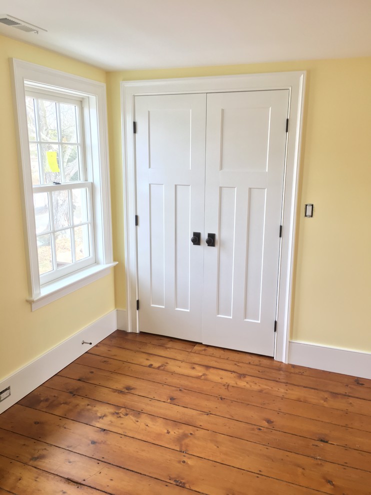 Mid-sized cottage guest medium tone wood floor bedroom photo in Bridgeport with yellow walls
