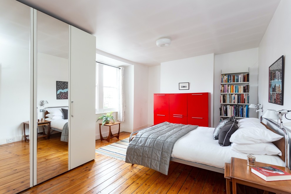 Imagen de dormitorio contemporáneo con paredes blancas, suelo de madera en tonos medios y suelo marrón