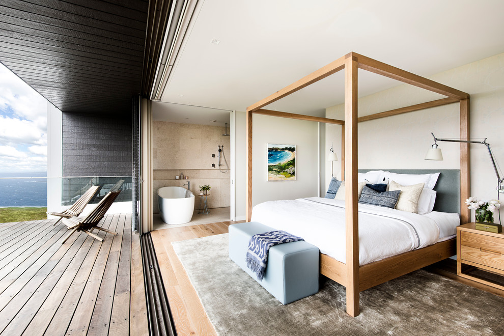 Ejemplo de dormitorio principal actual sin chimenea con paredes beige y suelo de madera clara