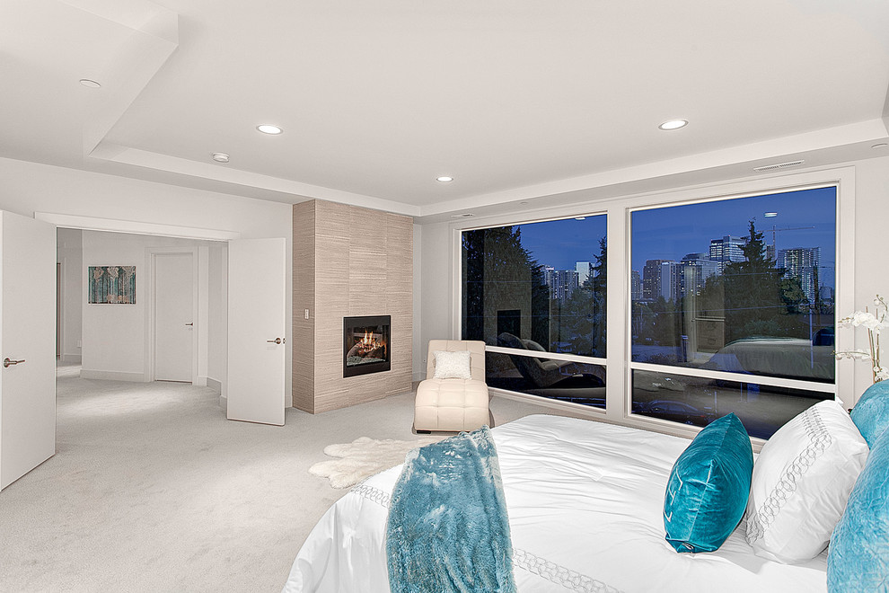 Inspiration for a large contemporary master bedroom in Seattle with white walls, carpet, a hanging fireplace, a tiled fireplace surround and beige floors.