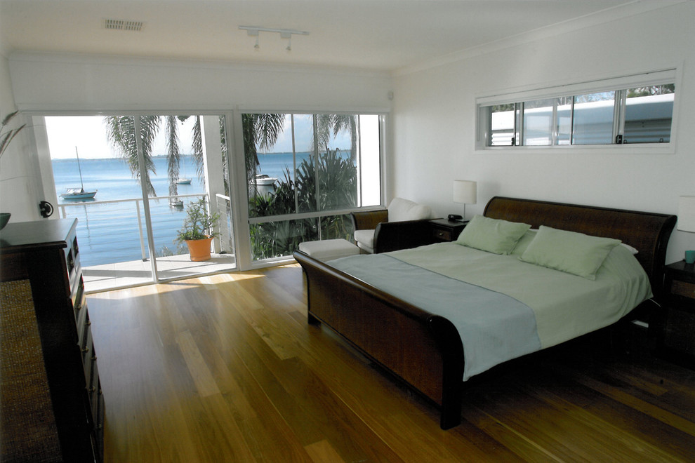 Immagine di una grande camera matrimoniale minimalista con pareti bianche e pavimento in legno massello medio