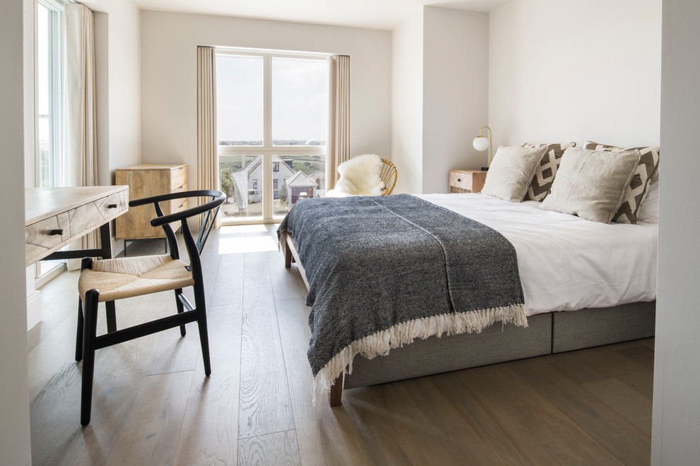 Imagen de habitación de invitados nórdica con paredes grises, suelo de madera en tonos medios y suelo marrón