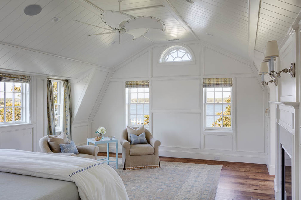 Großes Maritimes Schlafzimmer mit weißer Wandfarbe, braunem Holzboden, Kamin und Kaminumrandung aus Stein in Boston