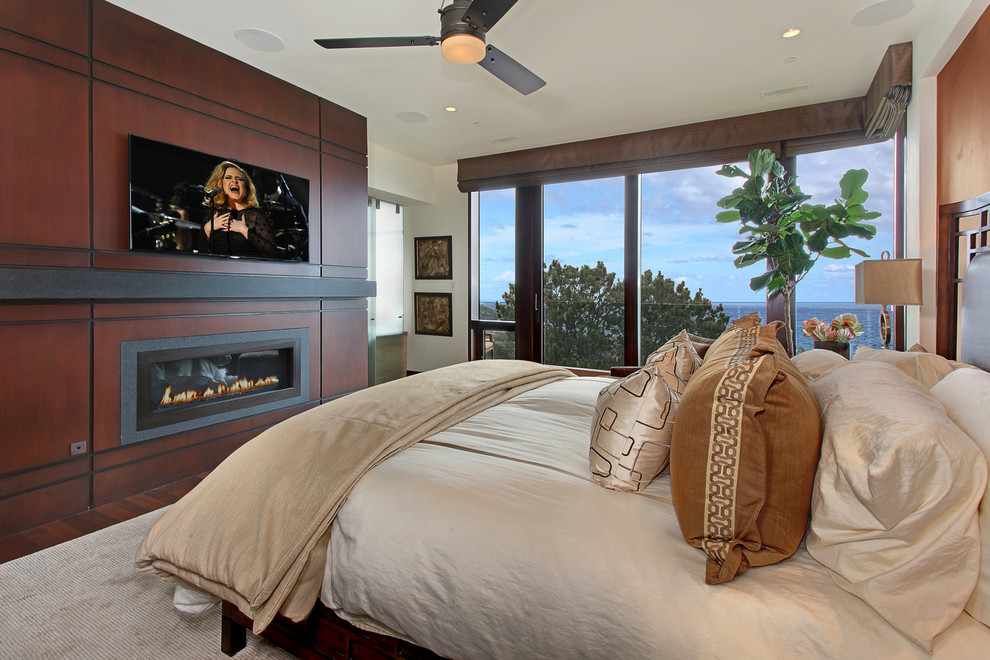 Mittelgroßes Modernes Hauptschlafzimmer mit Gaskamin, weißer Wandfarbe, dunklem Holzboden, Kaminumrandung aus Holz und braunem Boden in Orange County