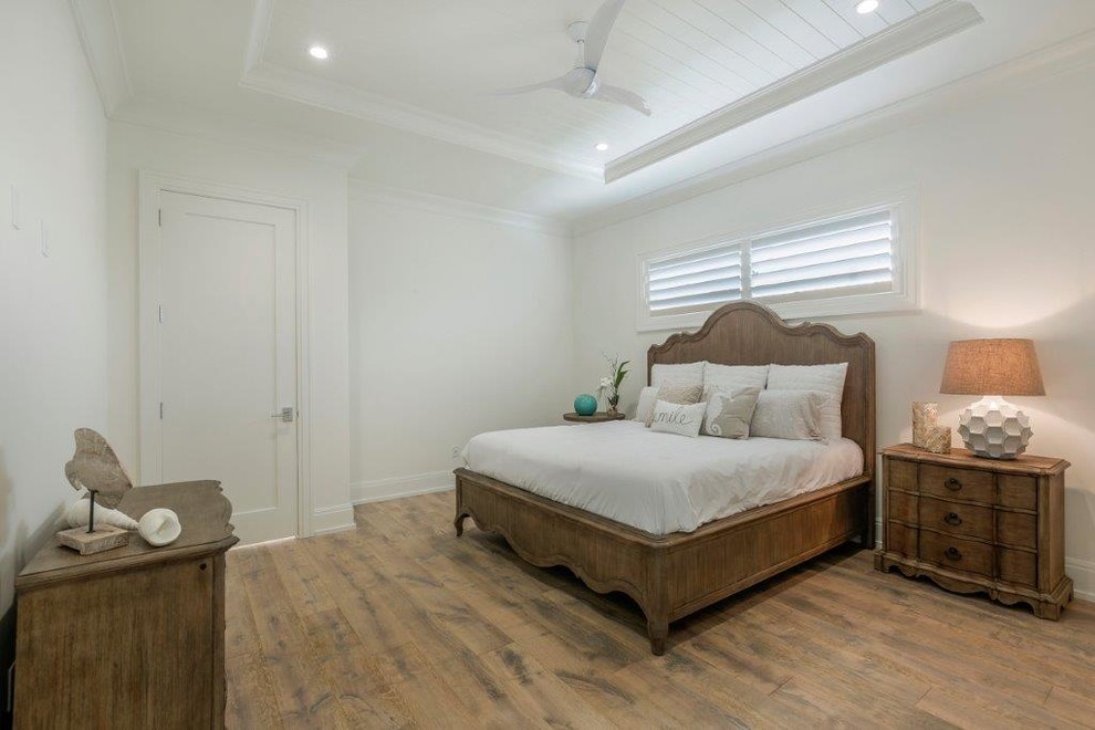 Design ideas for a large coastal guest bedroom in Miami with white walls, medium hardwood flooring and no fireplace.