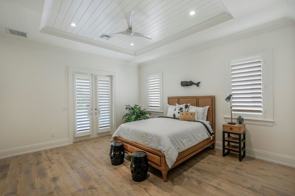 Ejemplo de habitación de invitados costera grande sin chimenea con paredes blancas y suelo de madera en tonos medios
