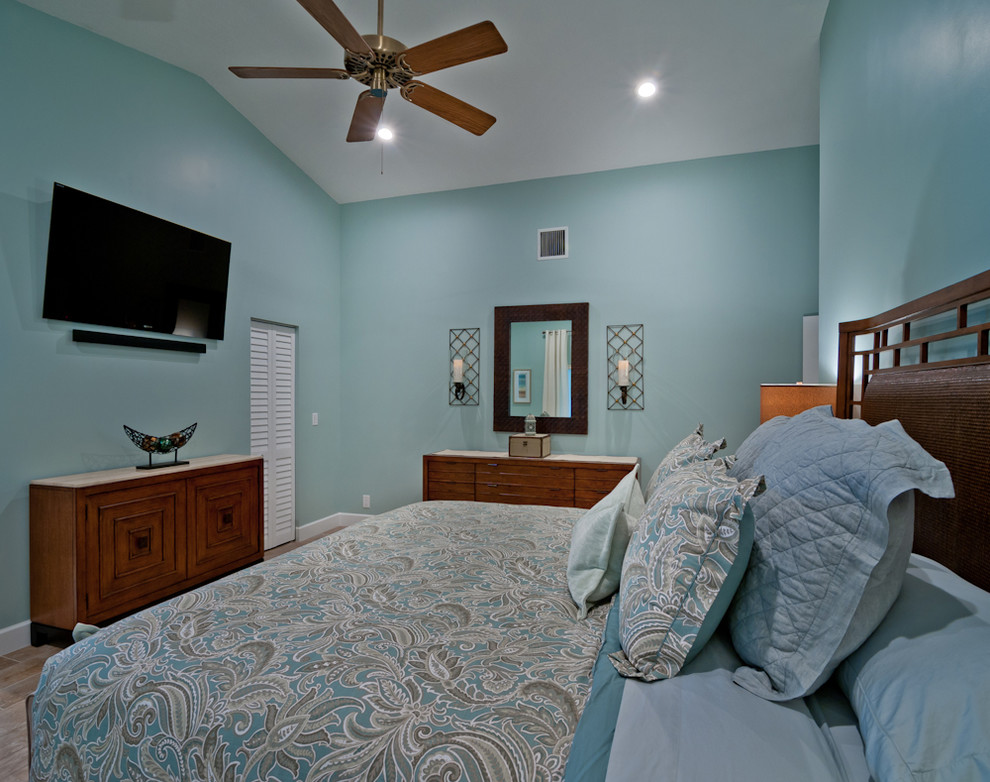 This is an example of a medium sized beach style master bedroom in Miami with blue walls and porcelain flooring.