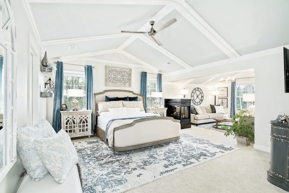 На фото: огромная хозяйская спальня в морском стиле с бежевыми стенами, ковровым покрытием, двусторонним камином, фасадом камина из плитки, бежевым полом, сводчатым потолком и деревянными стенами с