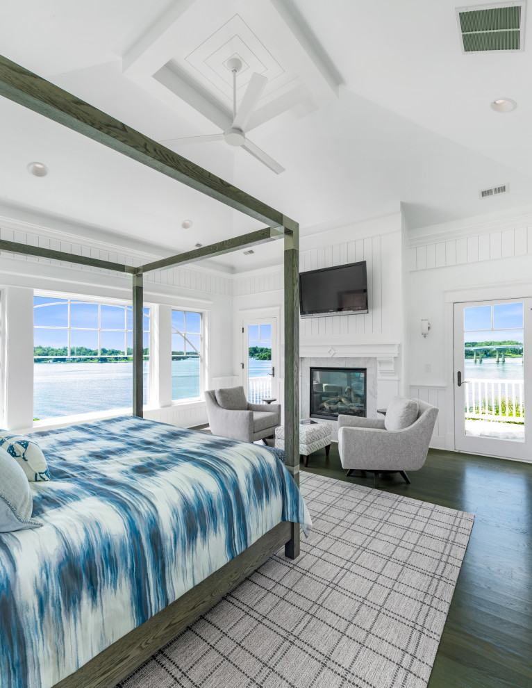 На фото: спальня в морском стиле с белыми стенами, темным паркетным полом, стандартным камином, коричневым полом и стенами из вагонки с