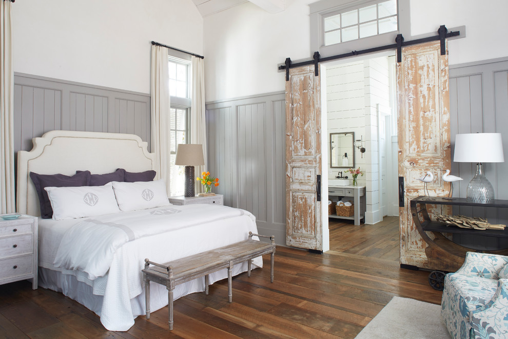 Immagine di una camera matrimoniale costiera con pareti bianche, pavimento in legno massello medio e pavimento marrone