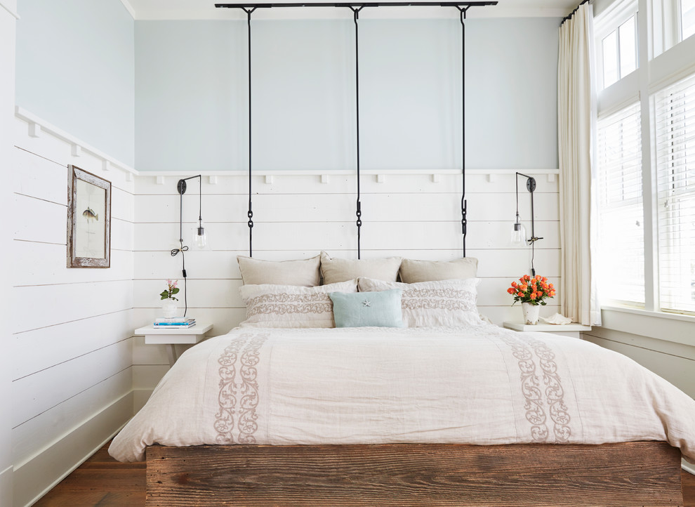Immagine di una camera da letto stile marino con pareti blu, pavimento in legno massello medio e pavimento marrone