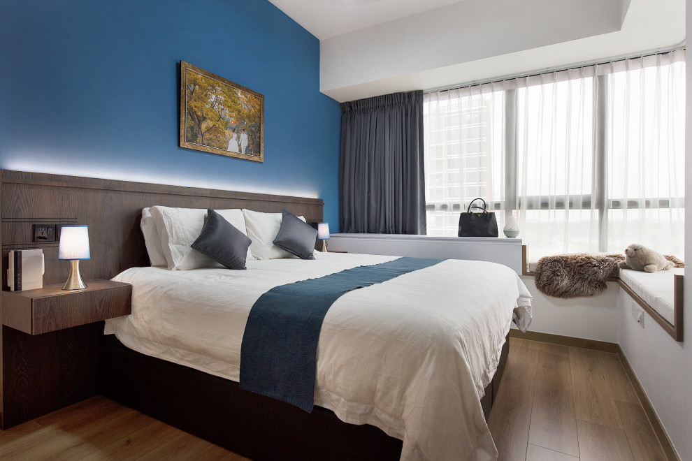 Diseño de dormitorio actual sin chimenea con paredes azules y suelo de madera en tonos medios