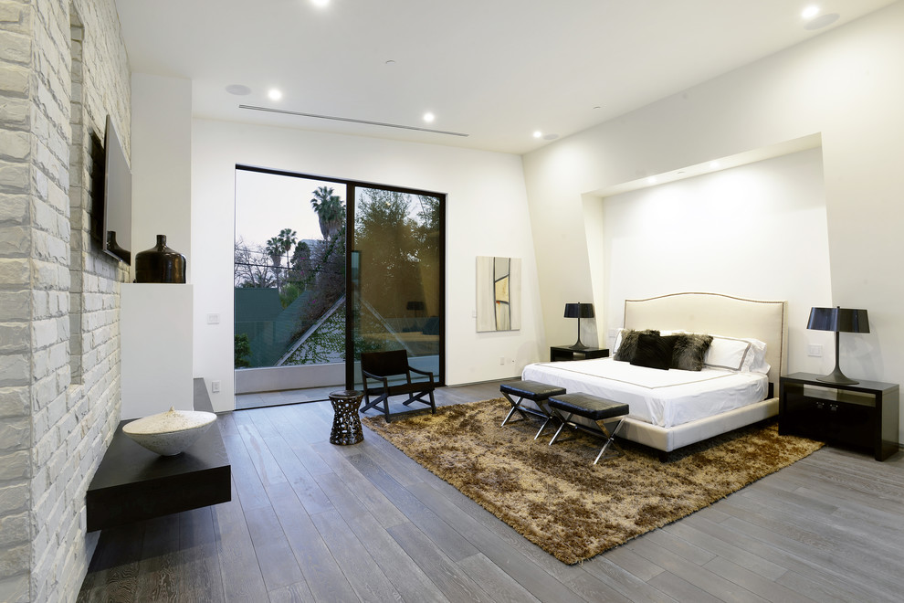Modelo de dormitorio principal actual grande con paredes blancas, suelo de madera oscura, suelo marrón, chimenea lineal y marco de chimenea de yeso