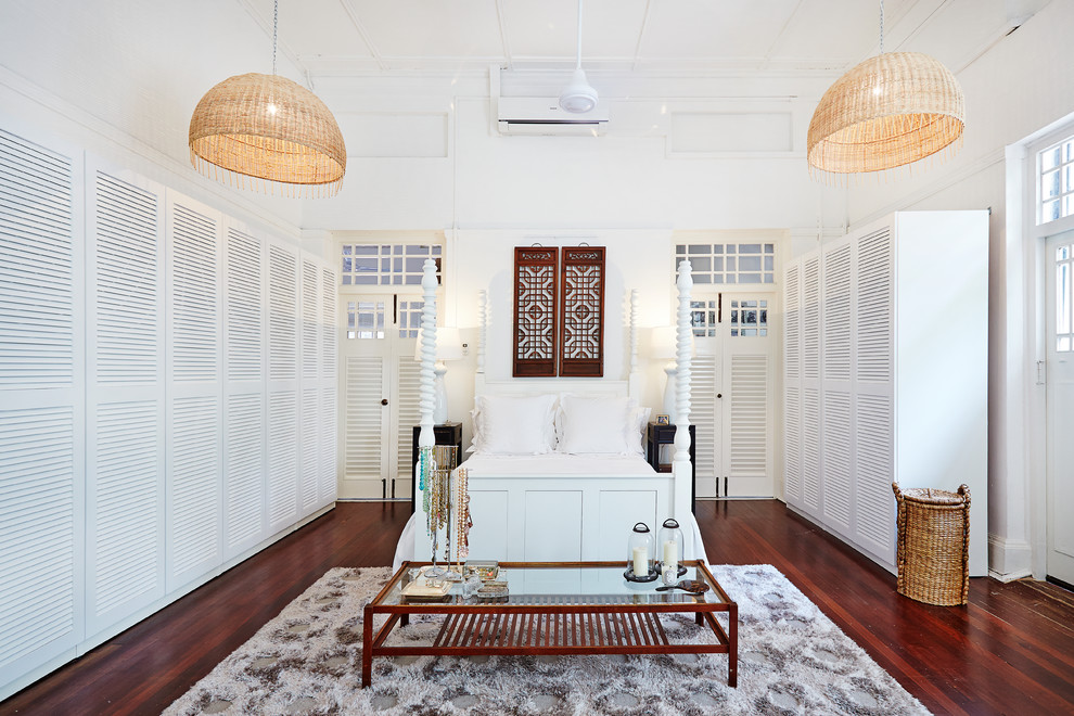 Diseño de dormitorio exótico grande con paredes blancas, suelo de madera en tonos medios y suelo marrón