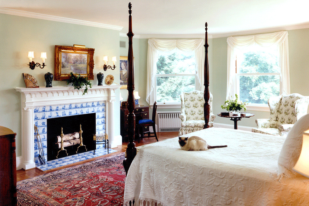 На фото: хозяйская спальня среднего размера в классическом стиле с паркетным полом среднего тона, стандартным камином, фасадом камина из плитки и зелеными стенами