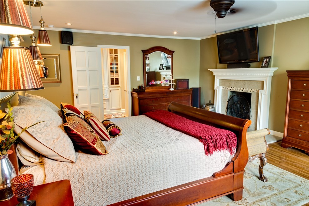 ウィチタにある中くらいな地中海スタイルのおしゃれな主寝室 (無垢フローリング、標準型暖炉、タイルの暖炉まわり、ベージュの壁、茶色い床) のレイアウト