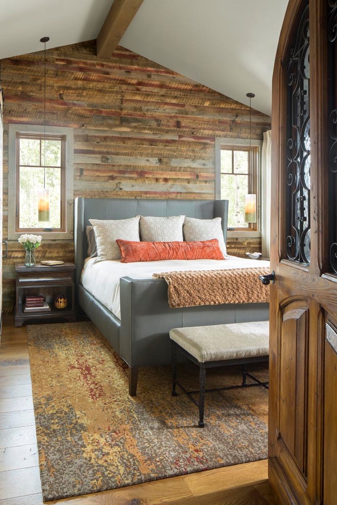 Mittelgroßes Uriges Hauptschlafzimmer mit braunem Holzboden, braunem Boden, brauner Wandfarbe, freigelegten Dachbalken und Wandpaneelen in Denver