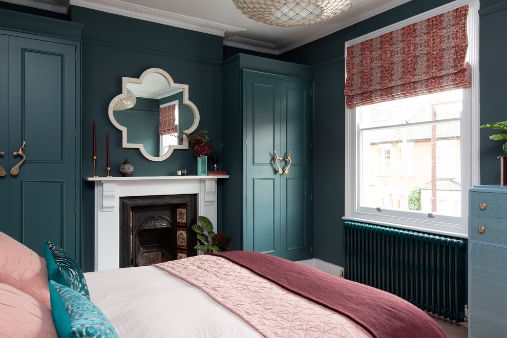 Cette image montre une chambre d'amis bohème de taille moyenne avec un mur bleu, une cheminée standard et un manteau de cheminée en métal.