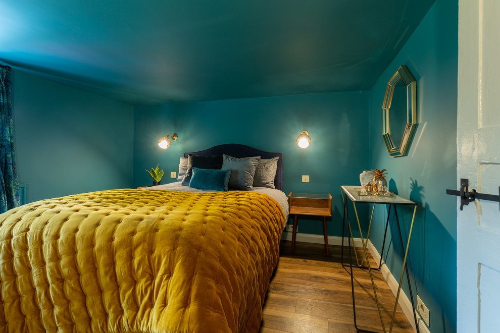 Diseño de dormitorio principal bohemio pequeño sin chimenea con paredes azules, suelo laminado y suelo marrón
