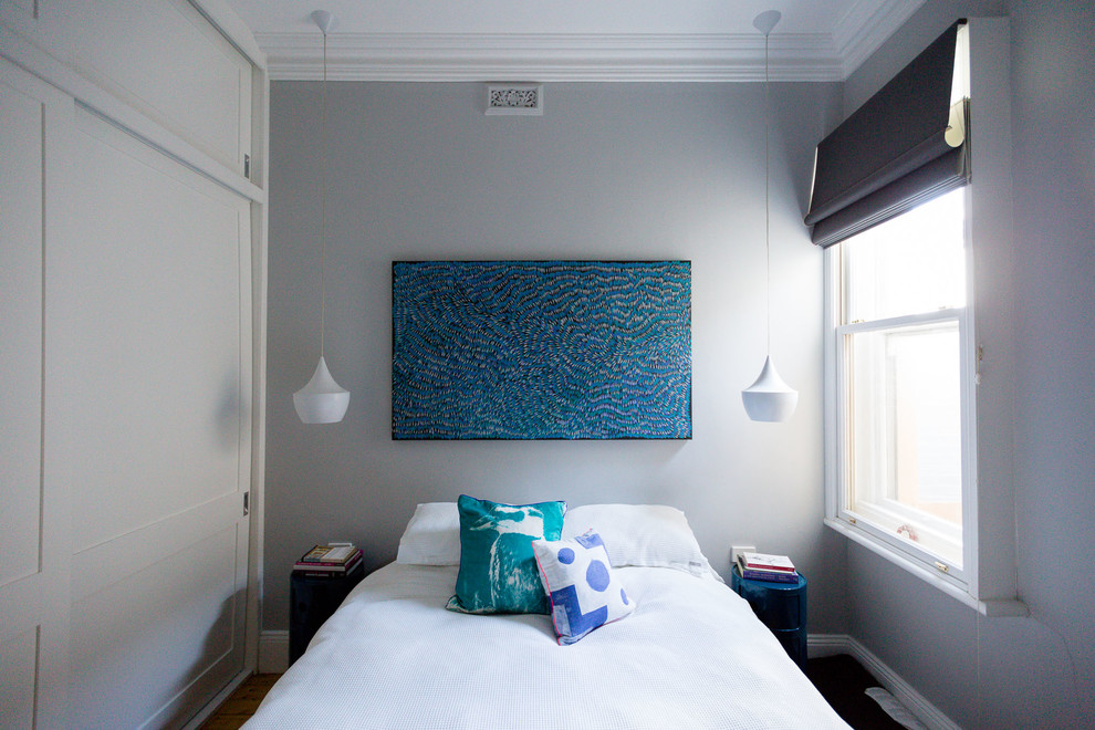 Idée de décoration pour une chambre design avec un mur gris et parquet foncé.