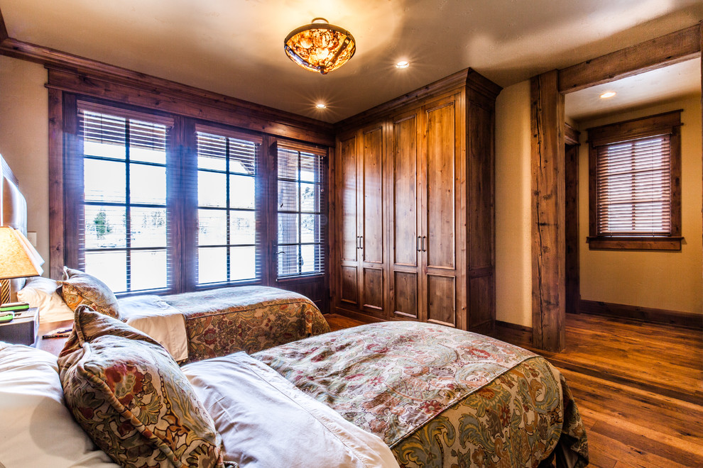 Aménagement d'une chambre d'amis montagne de taille moyenne avec un mur beige, un sol en bois brun et aucune cheminée.
