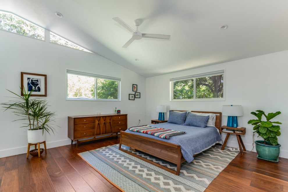 Photo of a midcentury bedroom in Austin with white walls, medium hardwood flooring, brown floors and a vaulted ceiling.