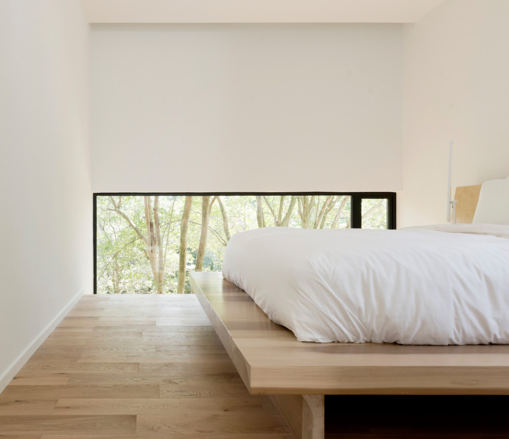Idées déco pour une chambre moderne avec un mur blanc, un sol marron et parquet clair.
