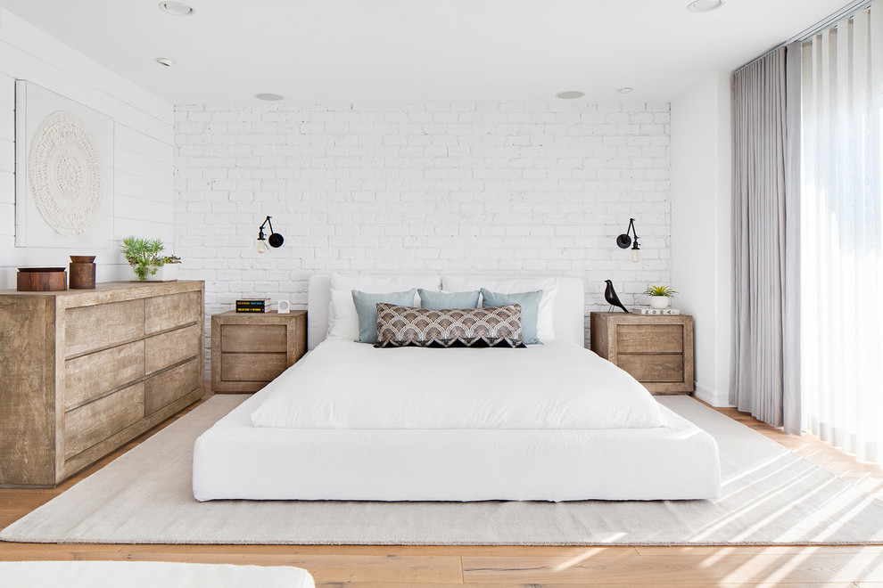 Diseño de dormitorio principal marinero grande sin chimenea con paredes blancas, suelo de madera en tonos medios y suelo marrón