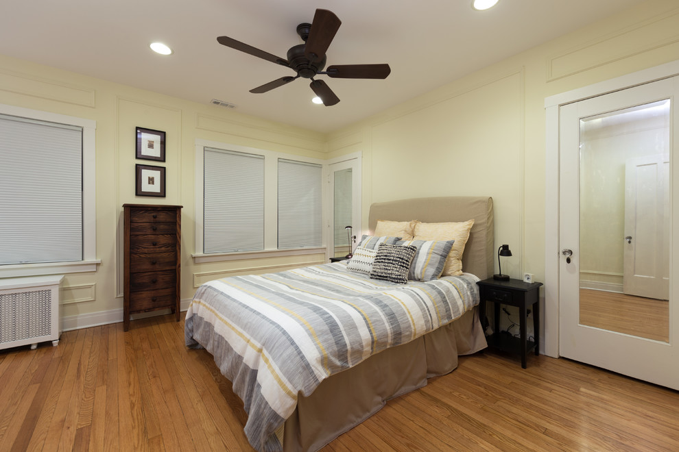 Example of a mid-sized transitional master medium tone wood floor bedroom design in Chicago with yellow walls and no fireplace