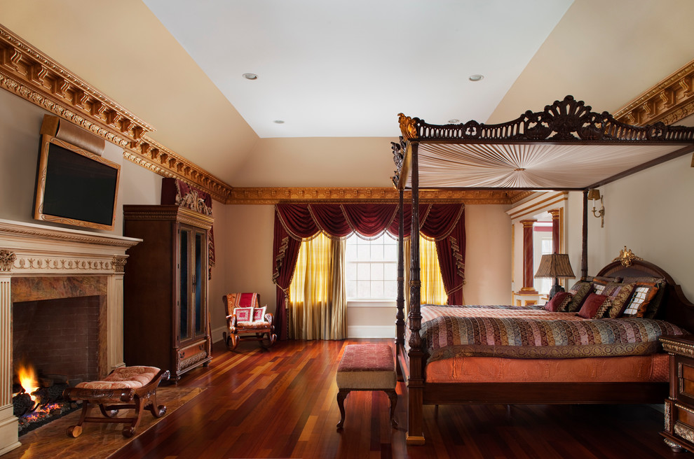 Großes Klassisches Hauptschlafzimmer mit beiger Wandfarbe, braunem Holzboden und Kaminumrandung aus Stein in New York