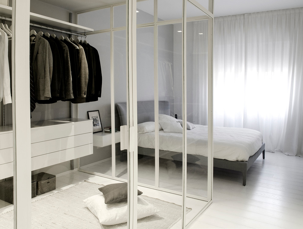 Cette image montre une chambre parentale design avec un mur blanc, parquet peint et dressing.