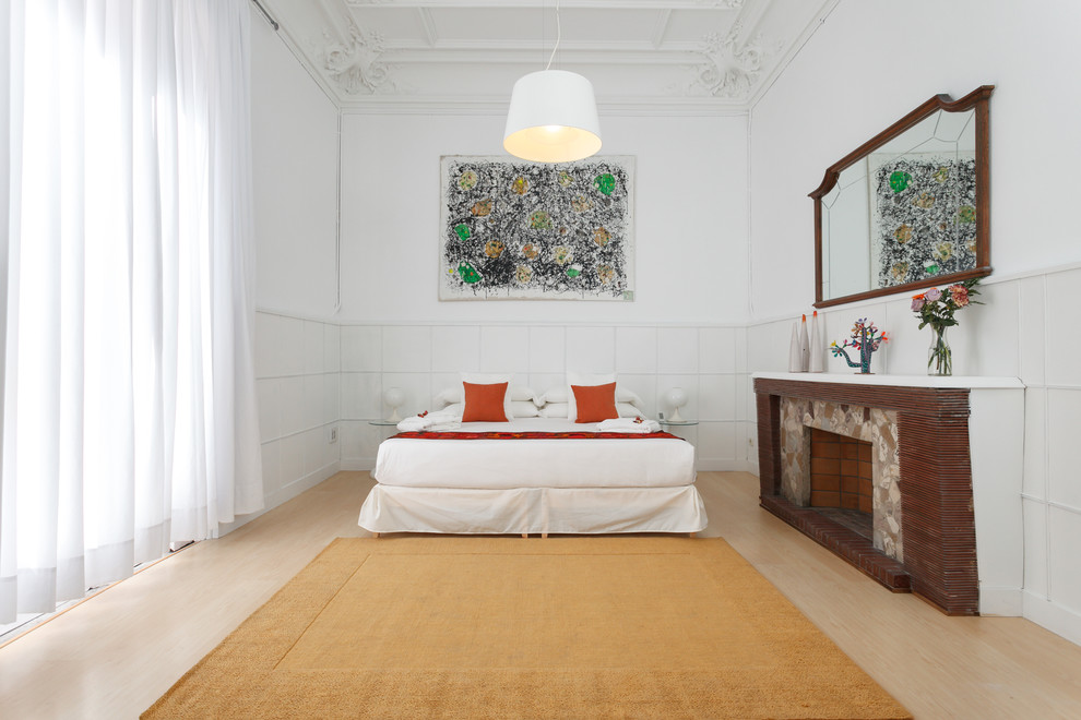 Diseño de dormitorio principal contemporáneo grande con paredes blancas, suelo de madera clara, todas las chimeneas y marco de chimenea de piedra