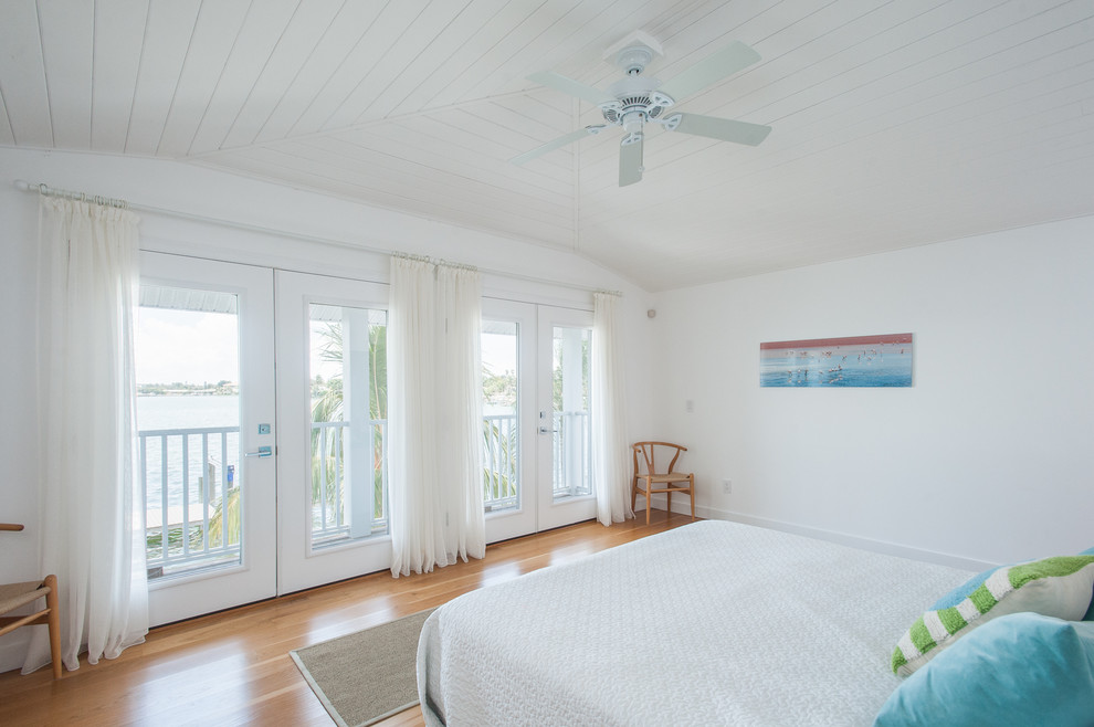 タンパにある広いビーチスタイルのおしゃれな主寝室 (白い壁、淡色無垢フローリング、暖炉なし、ベージュの床) のレイアウト