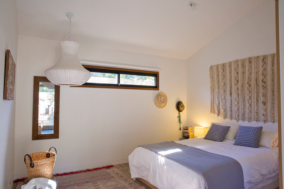 Large guest light wood floor and brown floor bedroom photo in Sydney with white walls