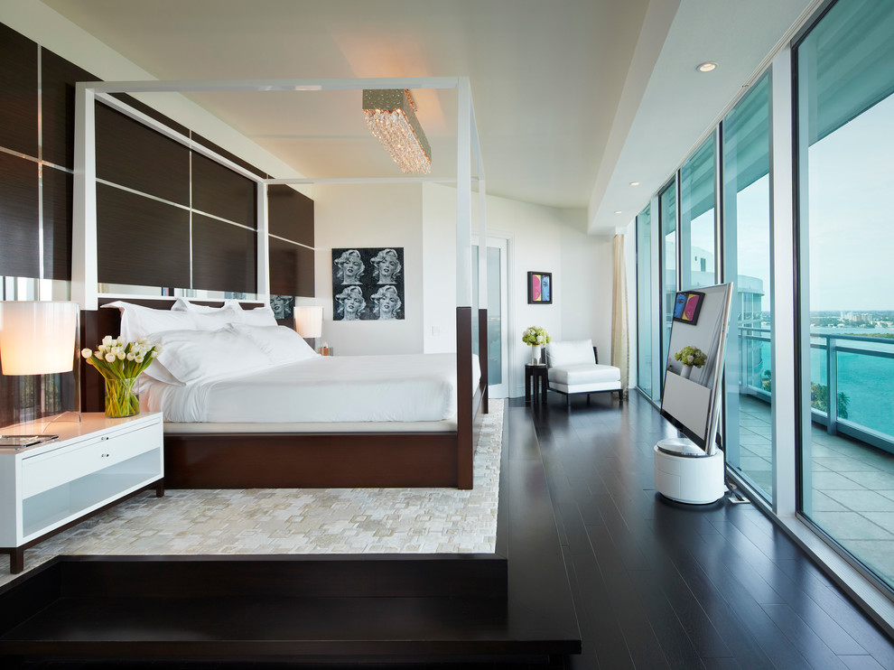 На фото: спальня в современном стиле с белыми стенами, темным паркетным полом и телевизором с