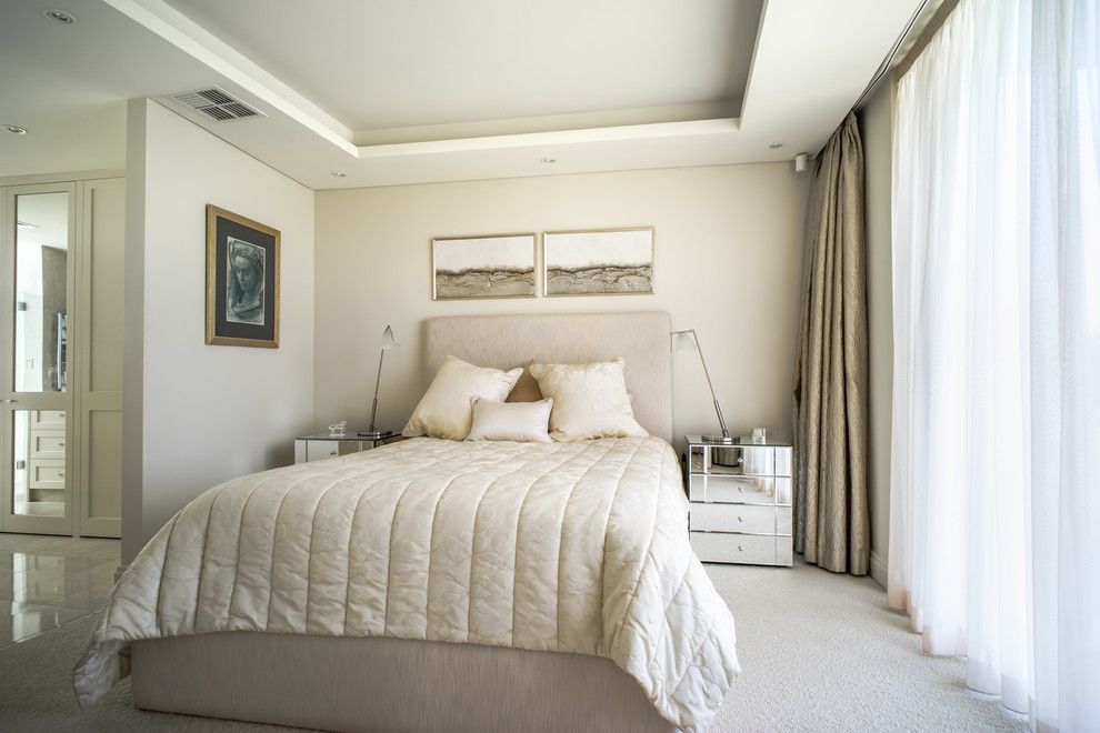 Immagine di una camera da letto design con pareti beige, moquette e pavimento beige
