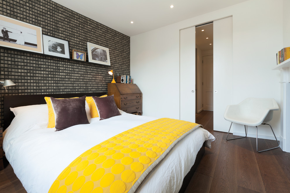 Inspiration for a contemporary grey and yellow bedroom in London with white walls, medium hardwood flooring and a feature wall.