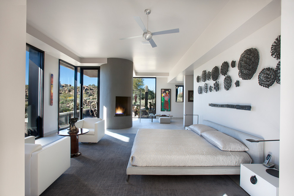 フェニックスにある広いコンテンポラリースタイルのおしゃれな主寝室 (白い壁、コーナー設置型暖炉、コンクリートの暖炉まわり) のインテリア