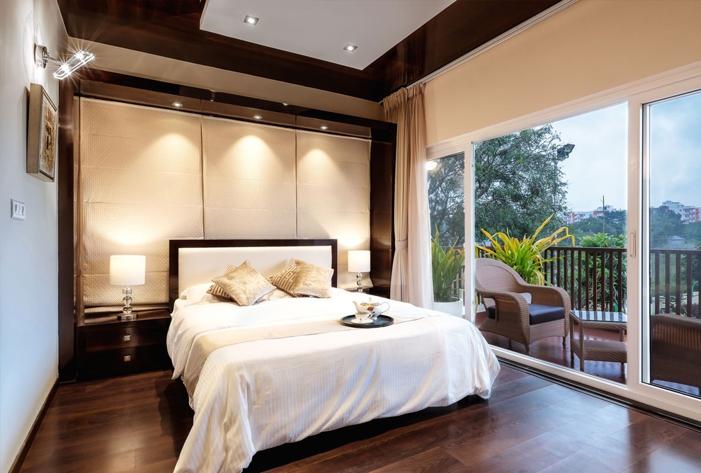This is an example of a medium sized contemporary master bedroom in Bengaluru with dark hardwood flooring and beige walls.