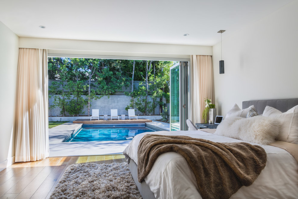 Modernes Hauptschlafzimmer ohne Kamin mit weißer Wandfarbe und braunem Holzboden in Los Angeles