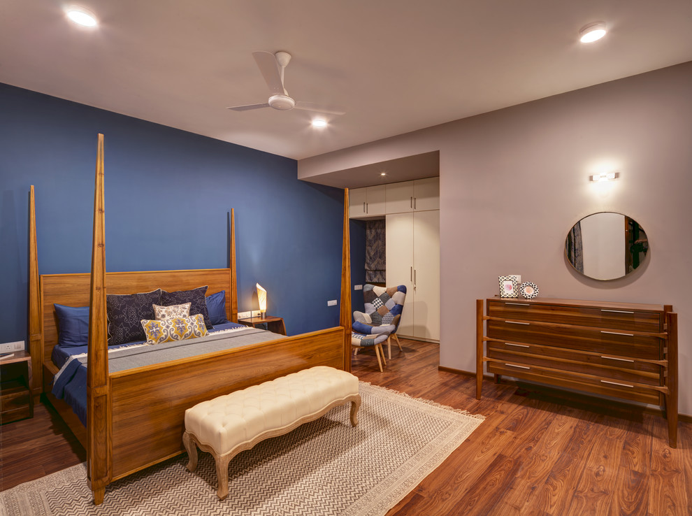 Ispirazione per una camera da letto design con pareti blu, pavimento in legno massello medio e pavimento marrone