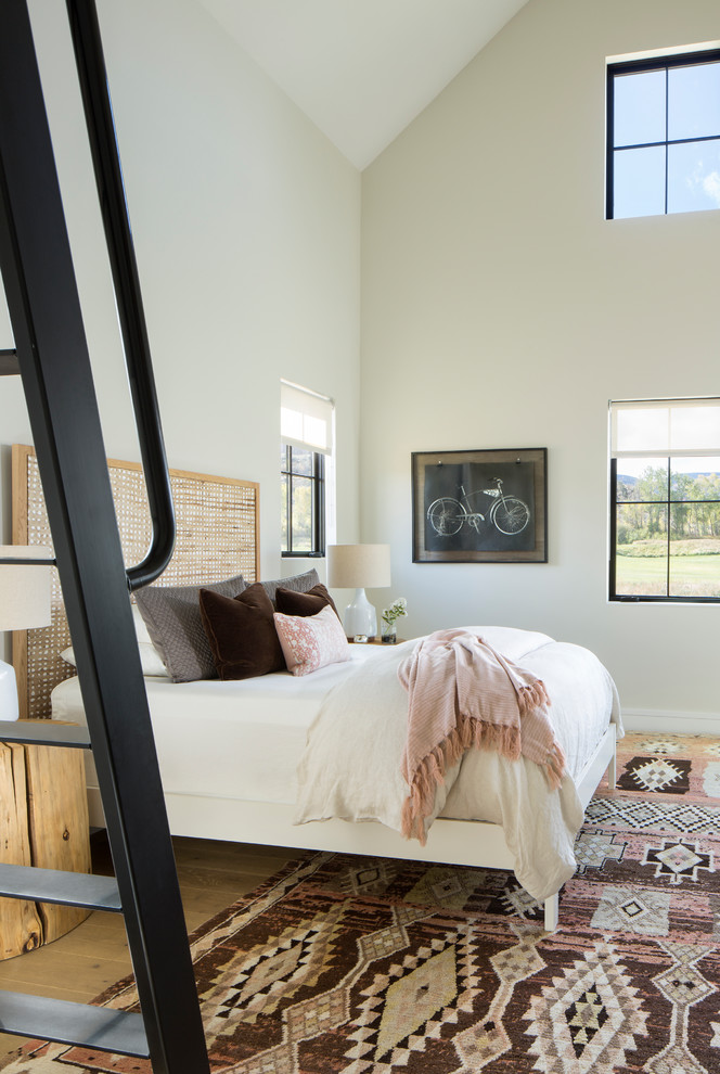 Contemporary loft bedroom in Denver with white walls, medium hardwood flooring and brown floors.