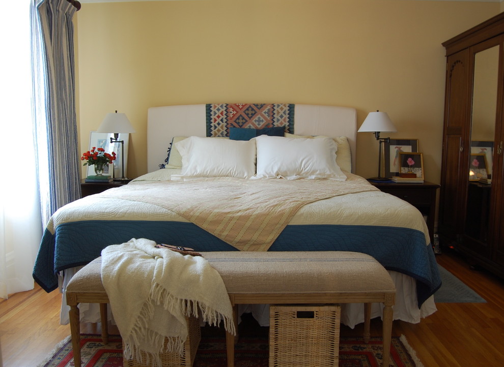 Diseño de dormitorio contemporáneo sin chimenea con paredes amarillas y suelo de madera en tonos medios